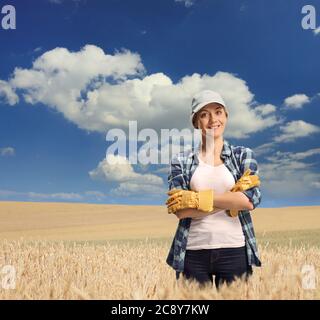 Jeune agricultrice dans un champ de blé, par une journée ensoleillée avec ciel bleu et nuages blancs Banque D'Images