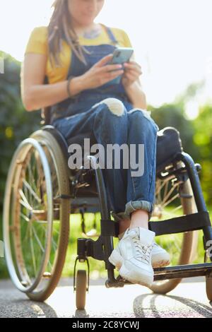 jeune femme attirante en fauteuil roulant, textant avec son téléphone mobile, handicap et concept d'emploi. gros plan rogné. arrière-plan flou. fre Banque D'Images