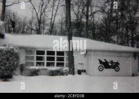 Belle photographie en noir et blanc vintage des années 1970 d'une maison familiale suburbaine commune à deux niveaux recouverte de neige pendant l'hiver. Banque D'Images