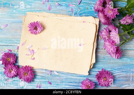 Carte de vœux avec vieux papier vierge et fleurs roses sur fond bleu en bois Banque D'Images