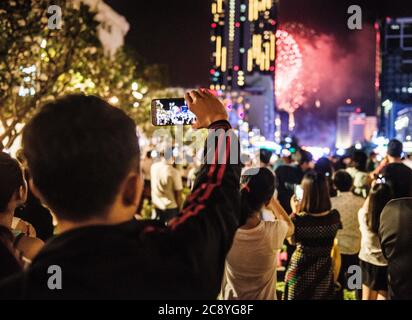 Personnes prenant des photos de feux d'artifice avec leur téléphone, Ho Chi Minh ville, Vietnam Banque D'Images