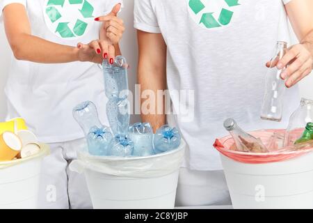 les volontaires placent les articles qui peuvent être recyclés dans les bacs appropriés. gros plan portrait, photo en studio, couple en choisissant le plastique et le verre pour les mettre int Banque D'Images