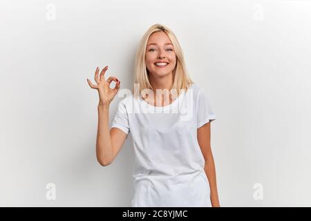 Portrait d'une femme souriante assez positive montrant le signe correct et sur fond blanc, portrait de gros plan, tout est ok, allright. Langage corporel Banque D'Images