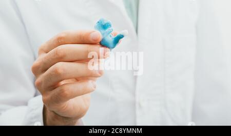 médecin tenant dans ses mains des embouts d'oreille moulés pour aides auditives individuelles pour son patient, gros plan. Solution auditive Banque D'Images