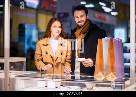 jeune couple caucasien dans le shopping, a décidé d'acheter des bijoux pour la femme dans le centre commercial.excitée redhaired femme et jeune homme barbu ensemble Banque D'Images