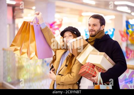 portrait de jeunes couples caucasiens adter shopping dans le centre commercial, au centre. belle femme à cheveux rouges et homme à barbe ensemble portant des sacs Banque D'Images