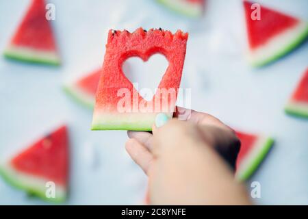 Watermelonhearts tranches sur les mains des femmes. Pastèque en tranches sur fond blanc. Flat lay, vue de dessus. Amour et soin. Banque D'Images