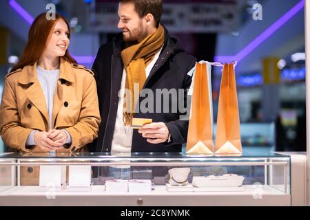 jeune couple caucasien dans le shopping, a décidé d'acheter des bijoux pour la femme dans le centre commercial.excitée redhaired femme et jeune homme barbu ensemble Banque D'Images