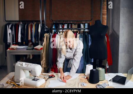 Gros plan talentueux tailleur dessine avec du savon, maquillage des motifs sur le tissu, studio de tir Banque D'Images