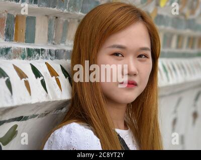 Une jeune touriste chinoise aux cheveux teints pose pour la caméra au célèbre temple Wat Arun de Bangkok. Banque D'Images