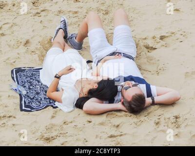 Un jeune couple se détendant sur la plage à côté de l' Sur la Tamise, sur la rive sud de Londres Banque D'Images