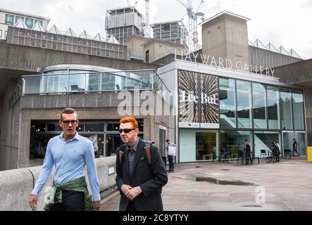 Deux hommes marchant devant l'exposition de Lee Bul à la Hayward Gallery du Southbank Center, Londres, Angleterre, Royaume-Uni Banque D'Images