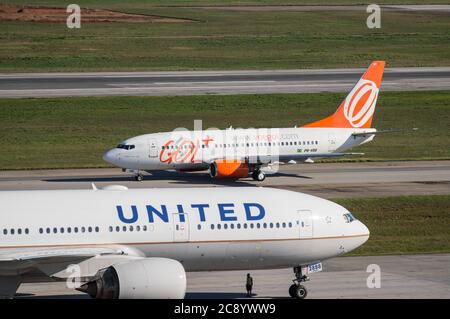 Compagnies aériennes GeD Boeing 737-700NG (PR-VBX - Old Livery) taxant la piste 27R alors qu'il passe par un Boeing 777 à l'aéroport international de Sao Paulo/Guarulhos. Aéroport. Banque D'Images