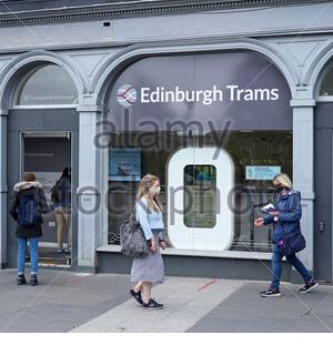 Les personnes qui portent des masques faciaux entrent et quittent la billetterie du tramway d'Édimbourg sur le pont Waverley, à Édimbourg Banque D'Images