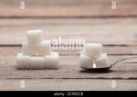 Le sucre raffiné en cubes dans une cuillère à thé sur une table en bois de vieux planches. Banque D'Images