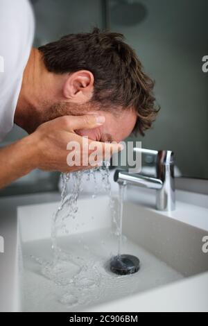 Homme se lavant le visage rinçant le savon de la peau dans l'évier sous l'eau froide courante du robinet, routine de soin de la peau du matin. Soin de beauté pour la peau pour hommes, lavage du visage Banque D'Images