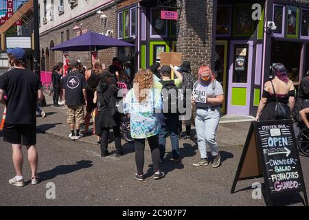 Un groupe de manifestants BLM démontrera devant la boutique Voodoo Donuts alors qu'ils marchent le long de la 3e Avenue vers le palais de justice fédéral à Portland, Oregon. Banque D'Images