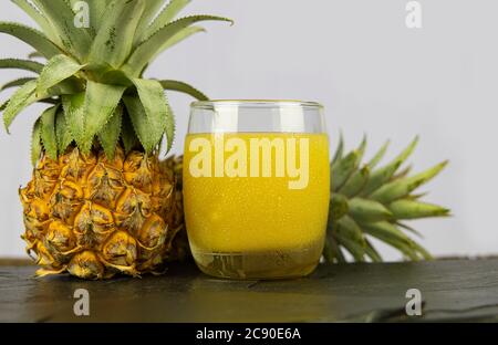 Un verre de jus d'ananas sur fond de table en pierre noire. Banque D'Images