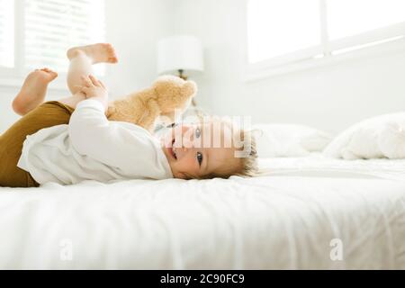 Petite fille couchée au lit avec son jouet ours en peluche Banque D'Images