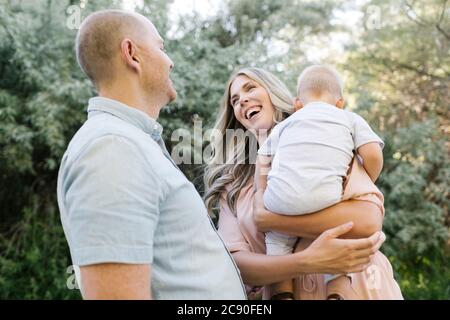 Parents heureux avec bébé fils riant dans le jardin Banque D'Images