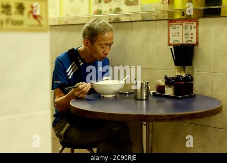 Hong Kong, CHINE. 28 juillet 2020. Senior ayant un bawl de Noodle chinois en s'y prenant pour vérifier son smartphone à l'intérieur du restaurant. Compte tenu de l'aggravation des infections à coronavirus à Hong Kong, le gouvernement va imposer toute la journée des restrictions de repas dans tous les restaurants de la ville à partir de demain mercredi heure de Hong Kong. 28 juillet 2020 Hong Kong.ZUMA/Liau Chung-ren crédit: Liau Chung-ren/ZUMA Wire/Alay Live News Banque D'Images