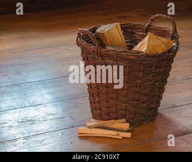 panier en osier avec bois haché et pile fendue sur bois plancher de la planche Banque D'Images