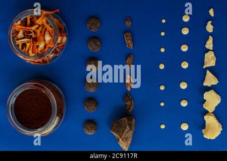 Vue de dessus de morceaux de chocolat sur fond bleu et noir et de poudre de cacao dans un pot en verre et de pelures d'orange pour les fruits confits Banque D'Images