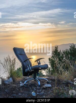 Chaise de bureau abandonnée dans un paysage de coucher de soleil. Banque D'Images