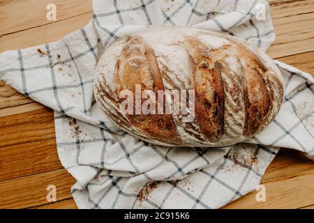 Pain à la pâte à sucre maison refroidi sur une serviette de thé qui est sur une planche à découper en bois, des fleurs sauvages séchées sont arrosées autour Banque D'Images