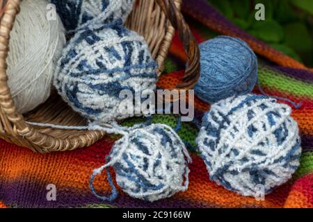 boules de laine bleue et blanche dans un panier en osier sur une couverture tricotée multicolore. Fond naturel. Affiche horizontale avec espace de copie. Fils pour tricot Banque D'Images