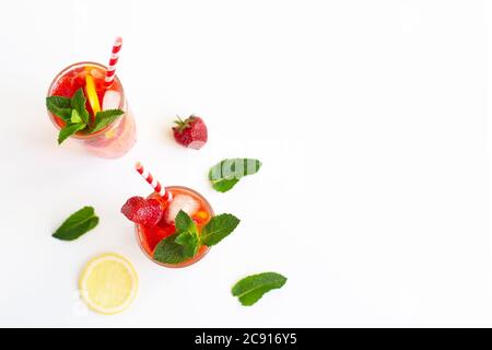 Jus de limonade aux fraises froides avec glaçons, menthe, citron, tube à cocktail et sur fond blanc. Boisson d'été froide. Cocktail de baies. Copier l'espace Banque D'Images