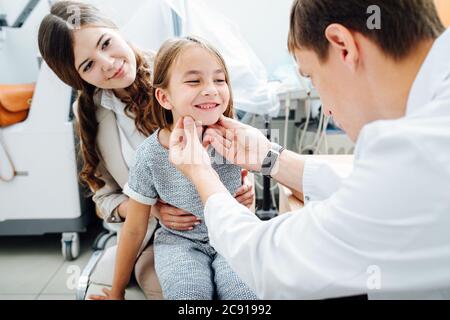 Bonne petite fille ludique en étant examinée par le pédiatre dans son bureau Banque D'Images