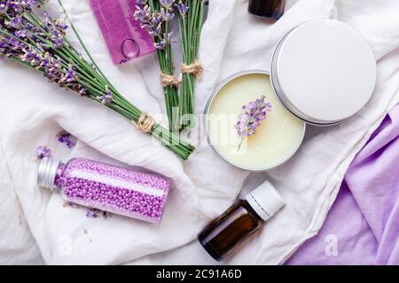 Set de produits cosmétiques lavande pour le soin de la peau. Produits de beauté naturels spa fleurs de lavande fraîches sur tissu. Lavande huile essentielle bouteille corps beurre Banque D'Images