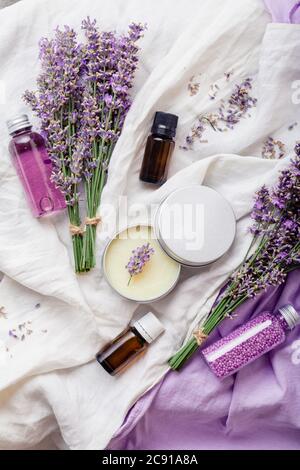 Set de produits cosmétiques lavande pour le soin de la peau. Produits de beauté naturels spa fleurs de lavande fraîches sur tissu blanc. Corps de bouteille d'huile essentielle lavande Banque D'Images