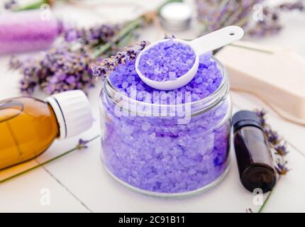 Sel de mer violet de lavande à l'huile essentielle et fleurs de lavande. Produits de bain lavande traitement d'aromathérapie sur fond de bois blanc. Soin de la peau Banque D'Images
