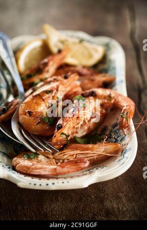 Crevettes entières grillées épicées gastronomiques à Malaga, en Espagne, servies sur un plat rustique en faïence en gros plan avec des ustensiles Banque D'Images