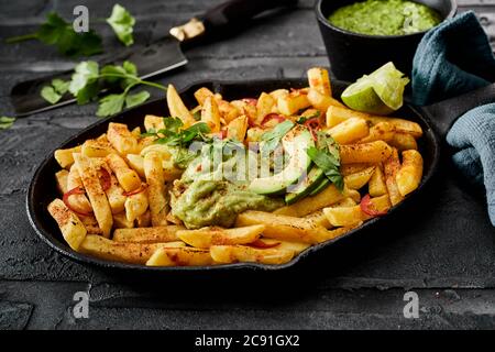 Il sert des chips de pommes de terre dorées croustillantes assaisonnées de piment et d'épices, nappées d'une sauce guacamole mexicaine et d'une poire d'avocat fraîche en gros plan pour un menu Banque D'Images