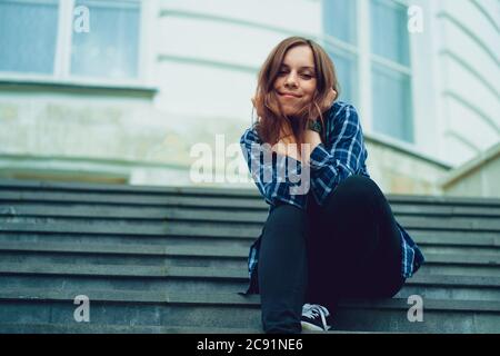 Jeune femme jolie pose sur les escaliers de manoir. Femme smiley adulte assise sur les marches du palais. Banque D'Images