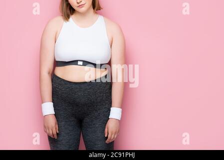 vue courte d'une fille en surpoids dans des vêtements de sport sur du rose Banque D'Images