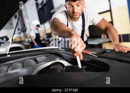 attention sélective du mécanicien de main dans la voiture de réparation de cap près de collègue dans l'atelier Banque D'Images