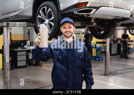 sélection de mécanicien gai dans le bouchon contenant la bouteille avec l'huile de voiture Banque D'Images