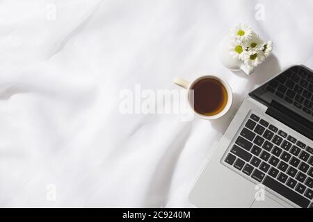 Vue de dessus de la scène du matin en toile de fond avec un bloc-notes, une tasse de thé et un vase de fleurs blanches avec espace pour le texte Banque D'Images
