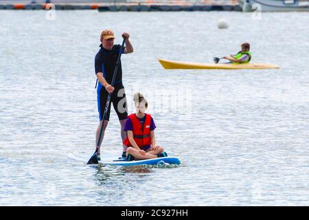 Lyme Regis, Dorset, Royaume-Uni. 28 juillet 2020. Météo Royaume-Uni. Paddle-boarders ayant l'amusement sur l'eau avec un kayak à la station balnéaire de Lyme Regis dans Dorset sur une journée de chaud ensoleillé sorts. Crédit photo : Graham Hunt/Alay Live News Banque D'Images