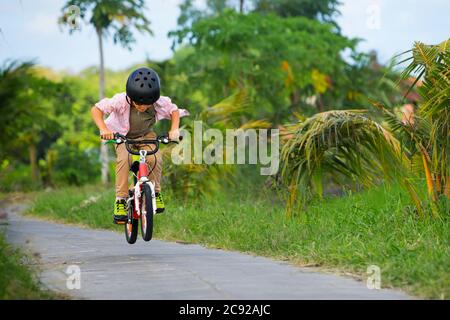 Randonnée à vélo. Jeune rider enfant dans un casque et des lunettes de soleil à vélo. Un enfant heureux s'amuse sur un sentier vide. Vie familiale active, sport, o Banque D'Images