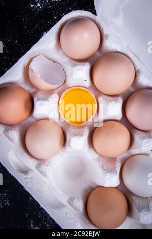 Image de jaune d'œuf dans un bol à côté d'œufs sains dans un plat ou un chiffon blanc et des ustensiles de cuisine. Banque D'Images