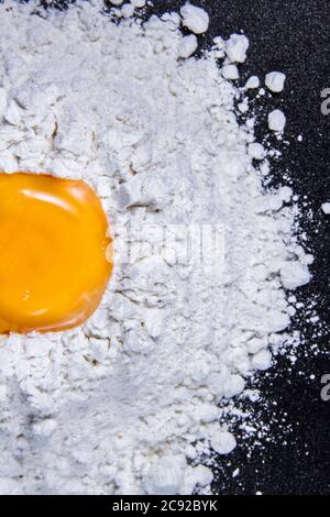 Oeufs cassés et farine pour cuire des gâteaux avec fond noir Banque D'Images