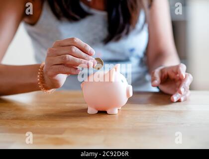 Femme mettant des pièces de monnaie à la banque de piggi. Banque D'Images