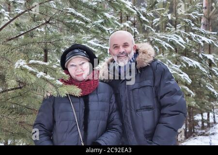 Portrait de couples d'âge moyen parmi les branches de jeunes pins en hiver Banque D'Images