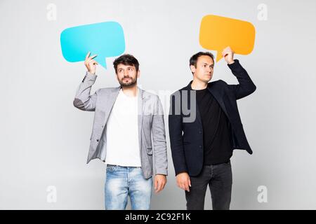 Portrait de deux hommes d'affaires satisfaits tenant des bulles de parole vides sur fond blanc Banque D'Images