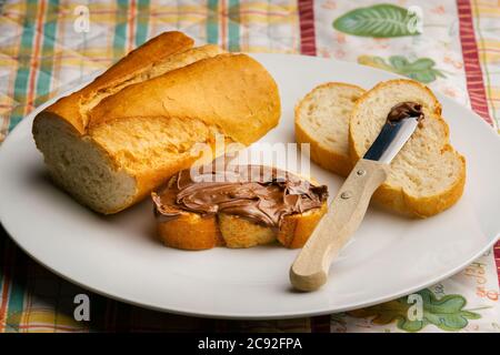 tranche de pain de pain avec pâte de chocolat tartiner avec le reste du pain et du petit couteau sur l'assiette Banque D'Images